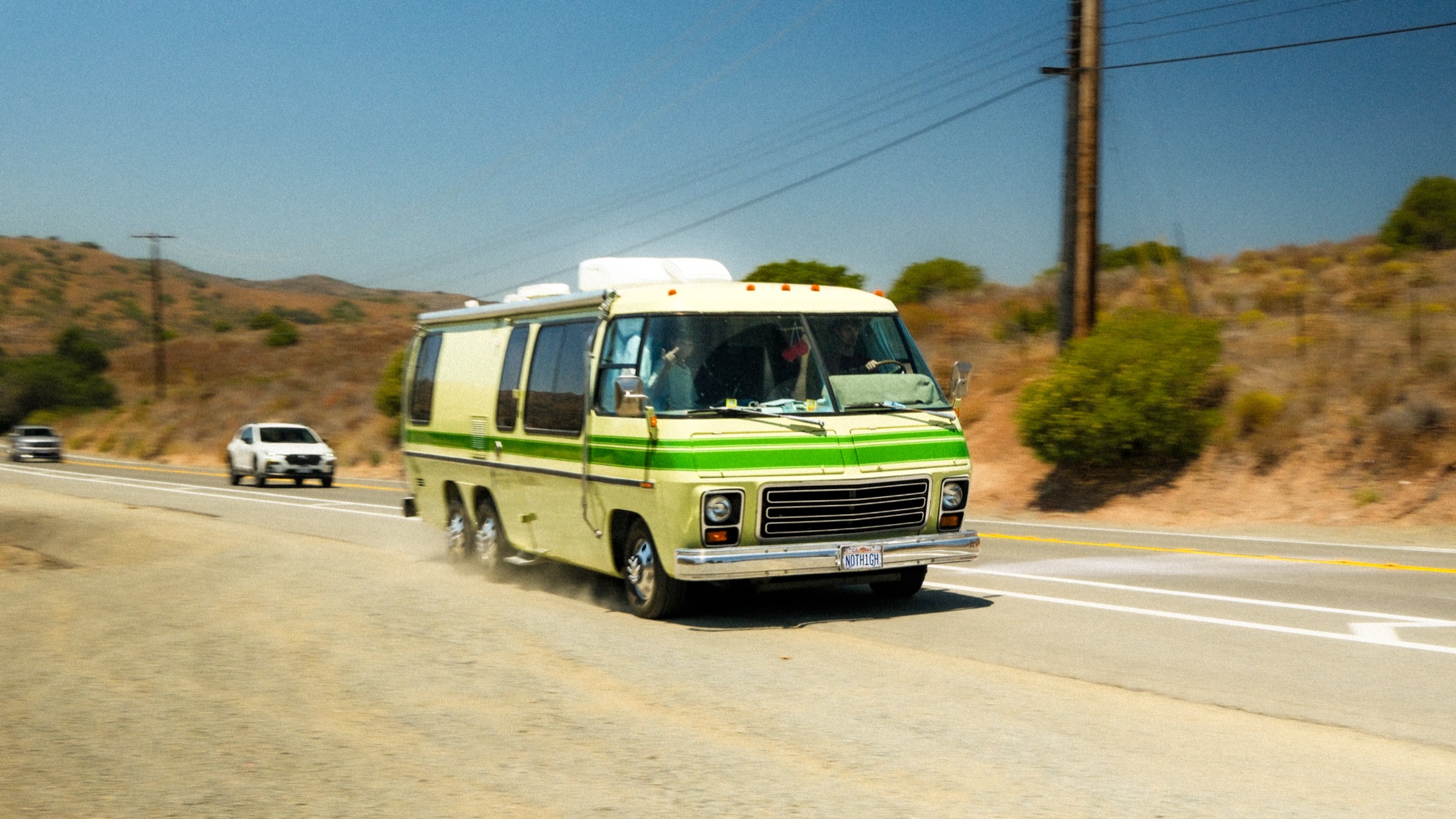 A vintage green RV speeding onto a Southern California highway